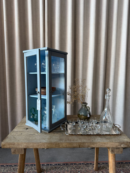 Ett charmigt litet väggskåp som passar fint att hänga i ett hörn då det är glas på två sidor. Du kan visa upp dina finaste småsaker eller häng det i badrummet och fyll det med parfymer, smycken och andra fina ting!Skåpet är sedan tidigare målat i en vacker blå/grå nyans med lite nött finish. 