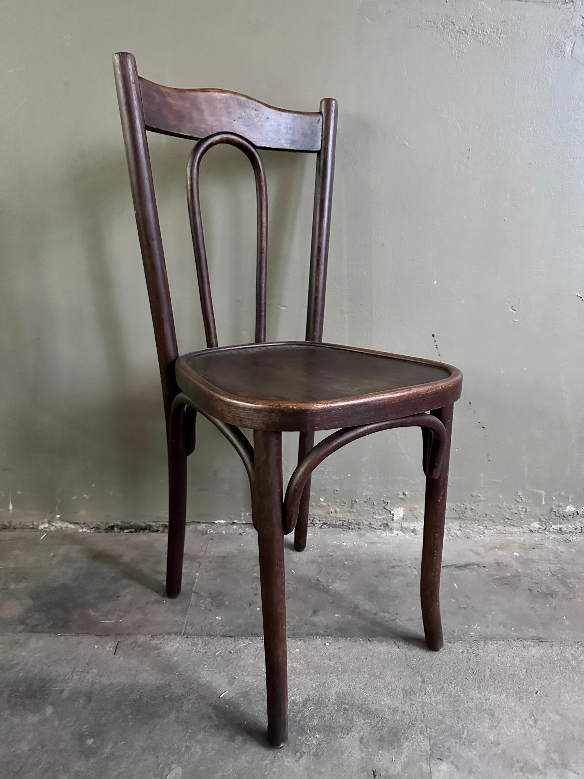 En styck äldre stol i trä. Bilden är tagen snett från sidan. 