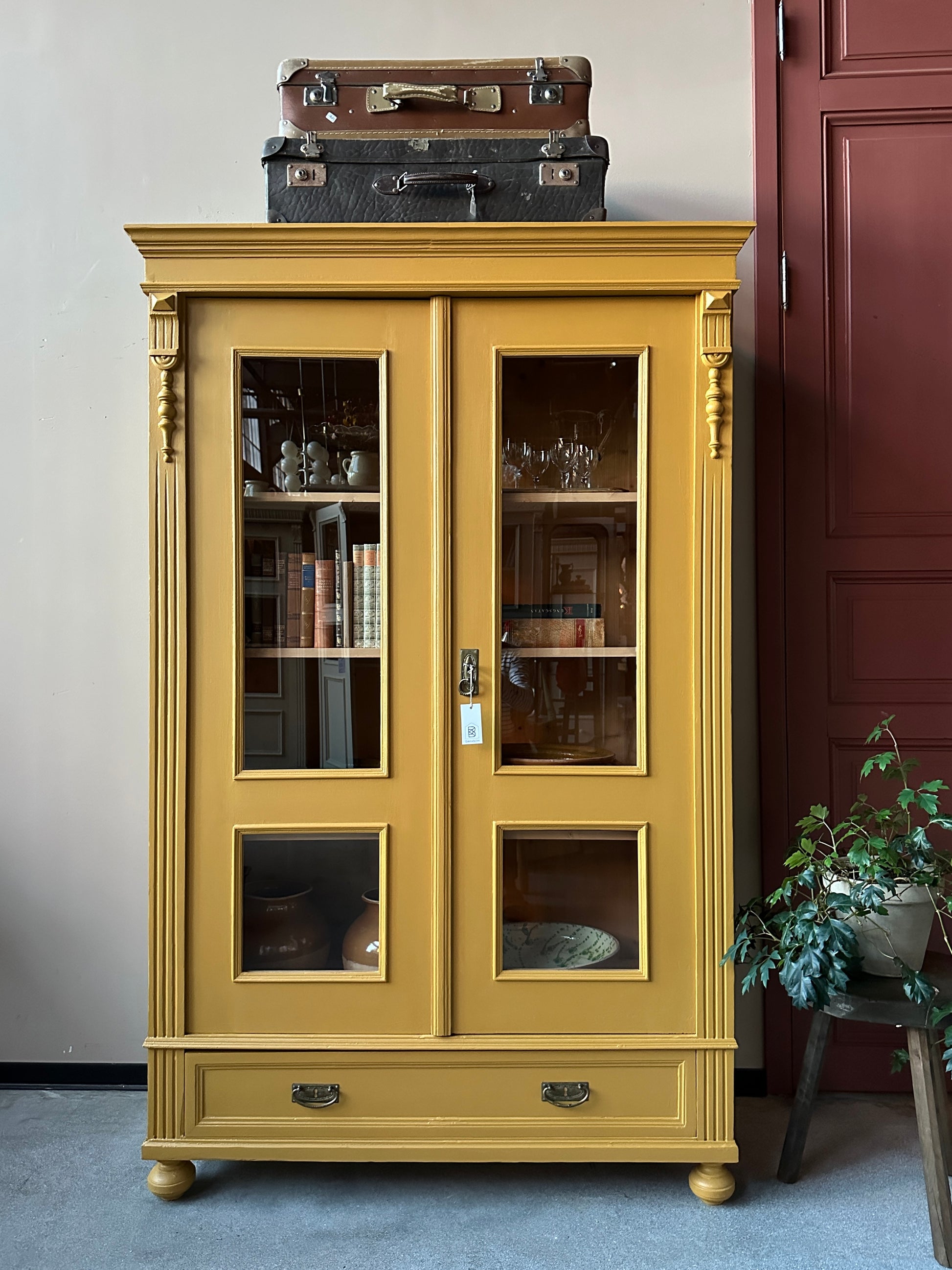 Ett gammalt, otroligt vackert vitrinskåp i Dakaboms ockragula kulör med fina detaljer i de raka formerna och det arbetade krönet. Skåpet har i dagsläget 3 st nya och fräscha hyllplan. 
Det har dessutom en bred praktisk låda längst ner. 
