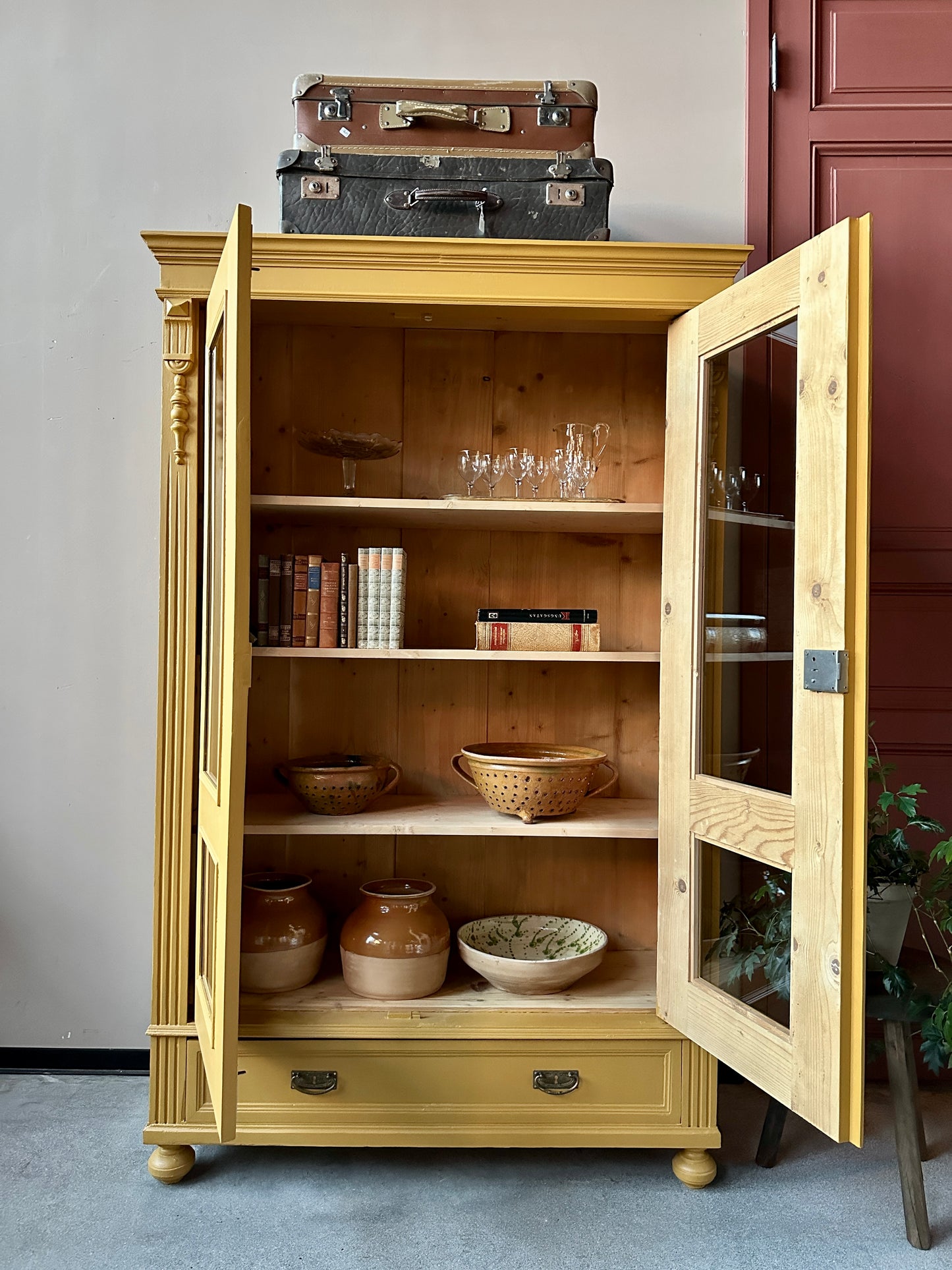 Ett gammalt, otroligt vackert vitrinskåp i Dakaboms ockragula kulör med fina detaljer i de raka formerna och det arbetade krönet. Skåpet har i dagsläget 3 st nya och fräscha hyllplan. 
Det har dessutom en bred praktisk låda längst ner. 