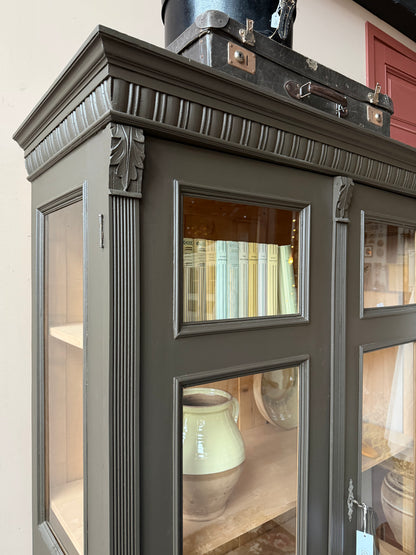 Ett gammalt, fantastiskt vackert vitrinskåp med fina detaljer i de raka formerna och det arbetade krönet. Skåpet har i dagsläget 3 st nya och fräscha hyllplan.Det har dessutom en bred praktisk låda längst ner med vackra porslinsknoppar. Skåpet är varsamt renoverat och slutligen penselmålat med en matt, vattenbaserad snickerifärg i en brun/grå kulör. 